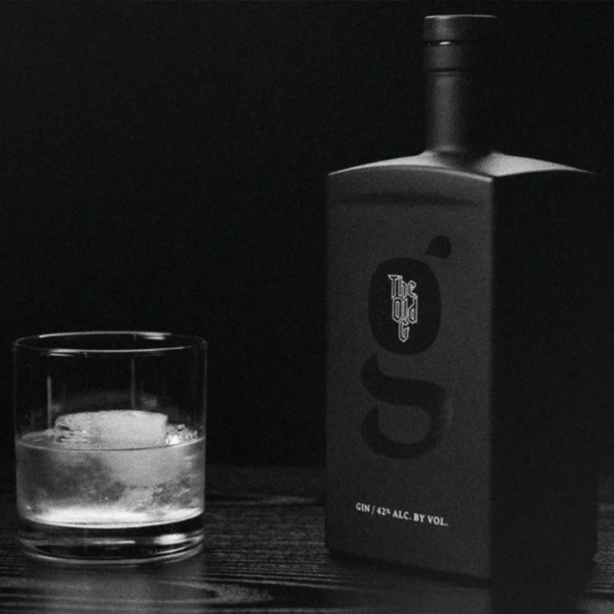 The Old G Gin bottle next to a glass of gin on rocks, showcasing premium distilled gin quality.