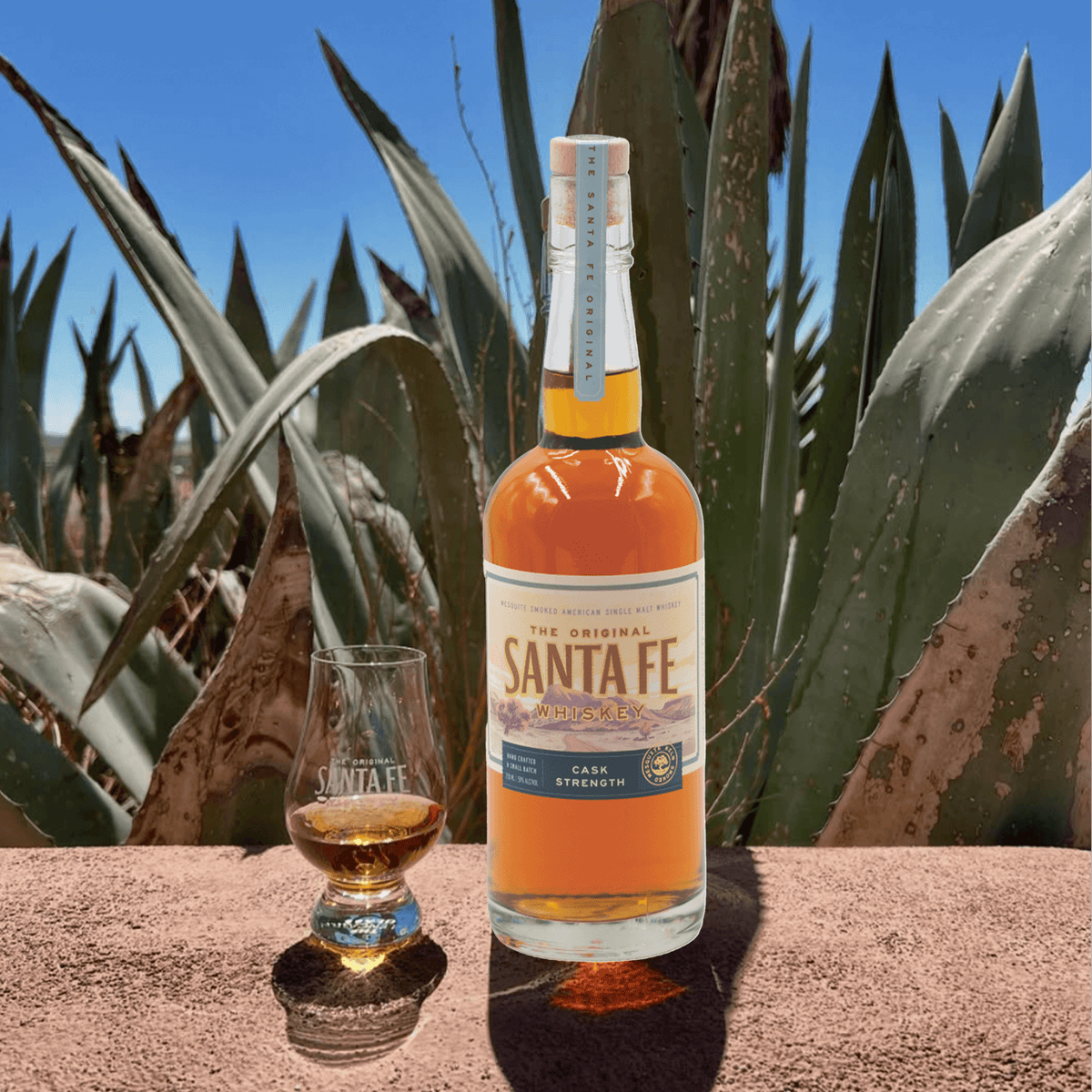 Bottle of The Original Santa Fe Cask Strength Single Malt whiskey with glass, featuring a desert background.