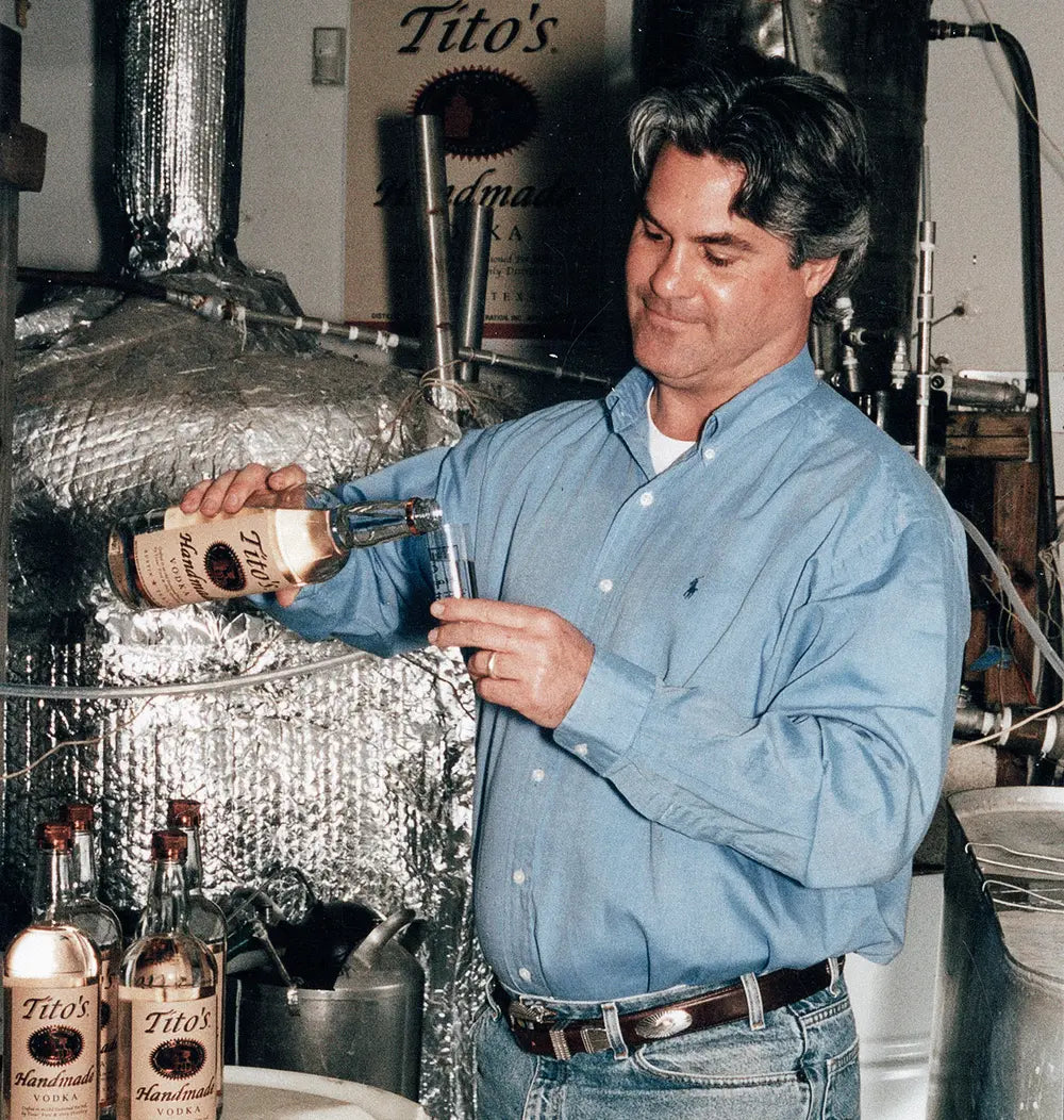 Tito Beveridge pouring Tito's Handmade Vodka in his distillery, showcasing craftsmanship and passion for quality spirits.