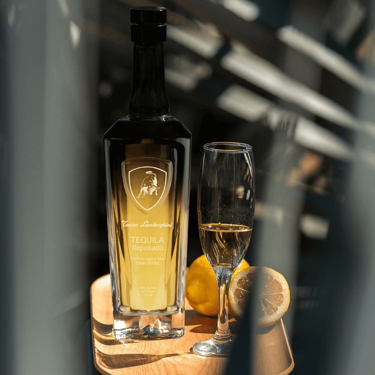 Tonino Lamborghini Reposado Tequila bottle with glass and lemon on wooden tray, showcasing Italian and Mexican craftsmanship.