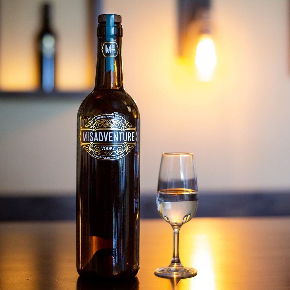 Bottle of Misadventure Sustainable Vodka with a glass, highlighting eco-friendly production.