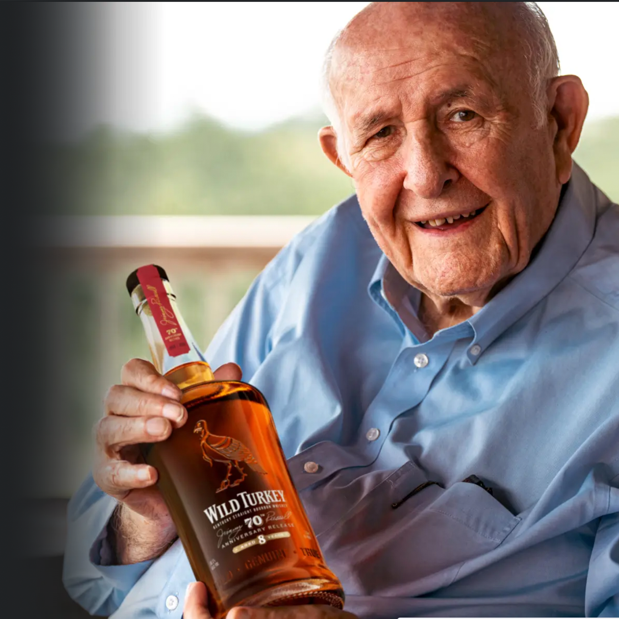 Jimmy Russell holding a bottle of Wild Turkey 70th Anniversary 8-Year Bourbon, celebrating his legacy.