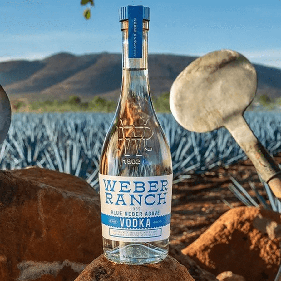 Weber Ranch 1902 Blue Weber Agave Vodka bottle in an agave field with mountains in the background.