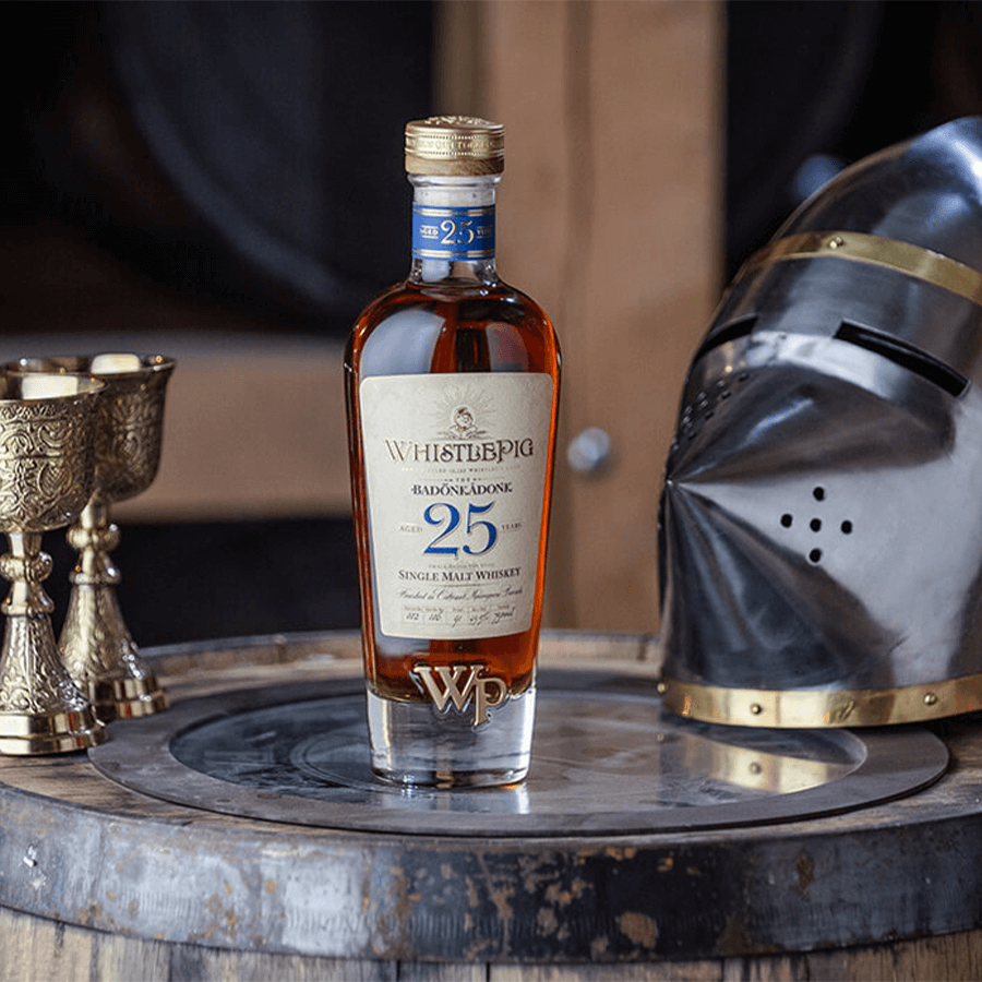 WhistlePig The Badonkadonk 25 Year Single Malt Whiskey bottle on a wooden barrel with a knight's helmet.