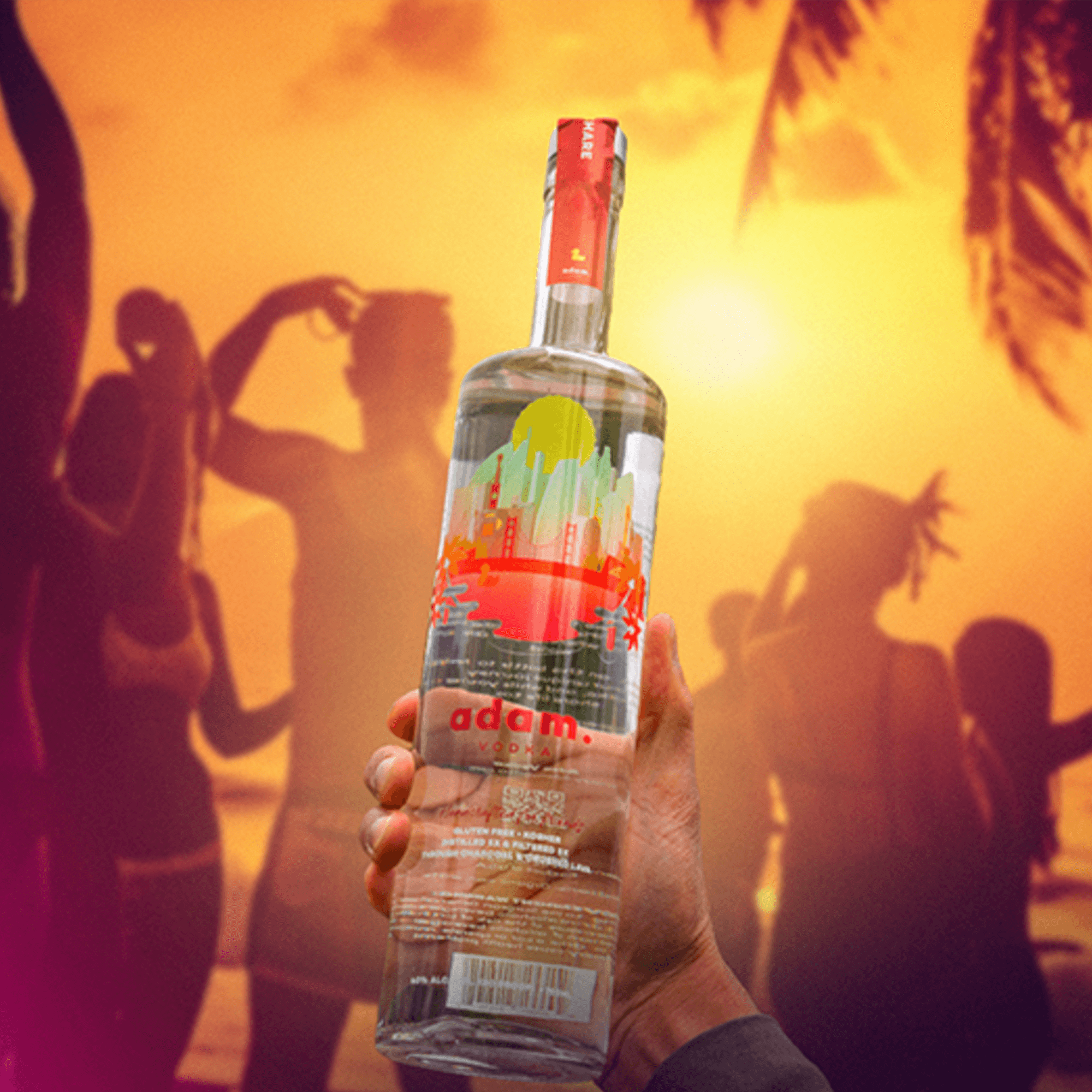 Hand holding a bottle of Adam Vodka against a vibrant sunset and people enjoying a beach party.