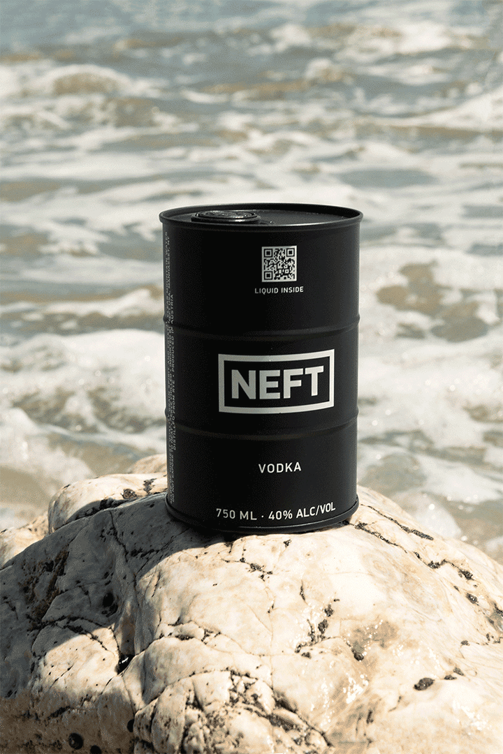 NEFT Black Barrel Vodka can on a rock by the ocean, showcasing its sleek design and premium quality ingredients.