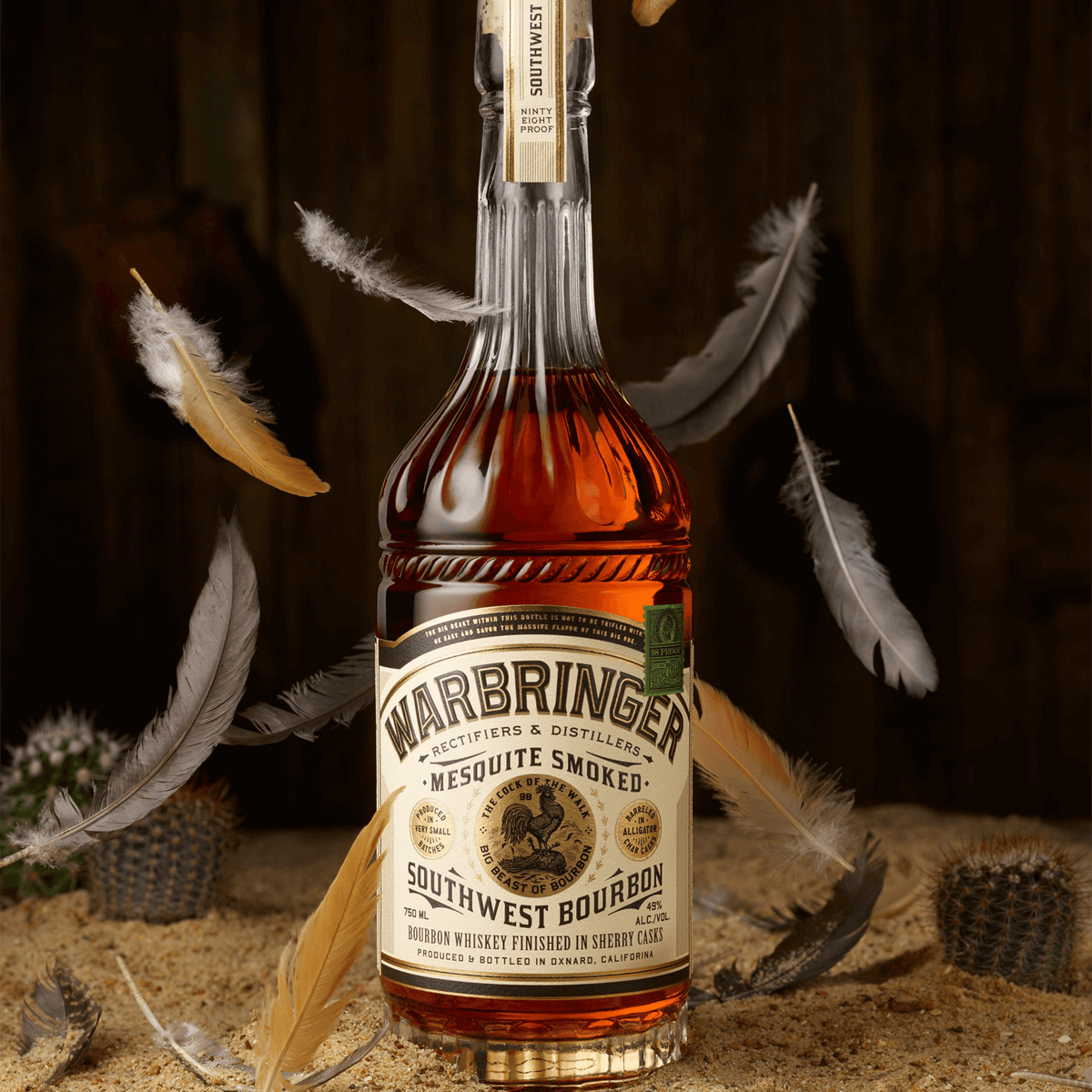 Warbringer Mesquite Smoked Southwest Bourbon bottle surrounded by feathers, showcasing its rich amber color and unique branding.