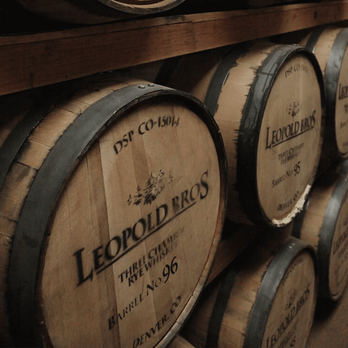 Leopold Bros whiskey barrels stacked in storage, showcasing craftsmanship and aging process in Denver.