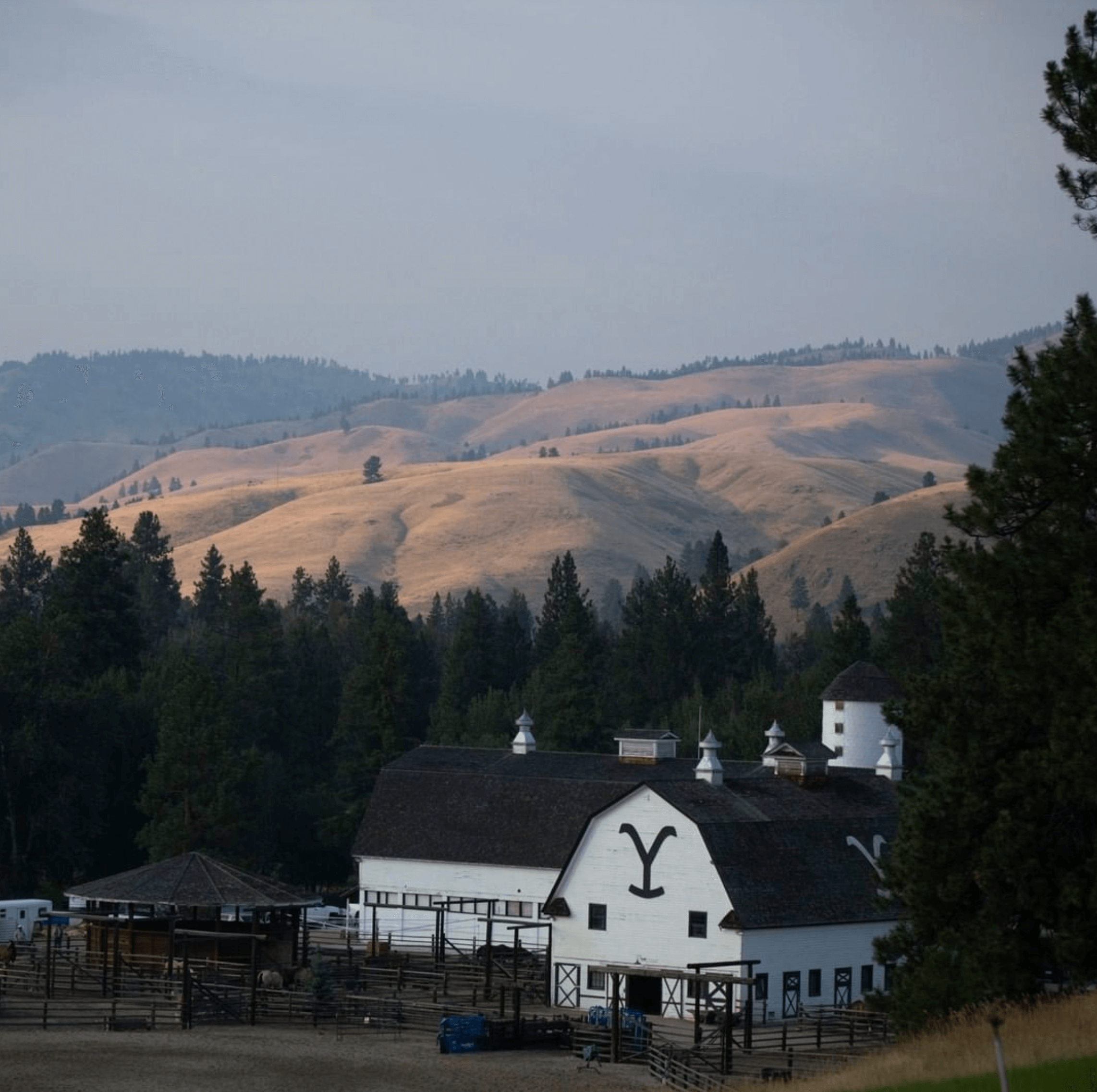 Scenic view of a ranch barn with rolling hills in the background, showcasing natural beauty.