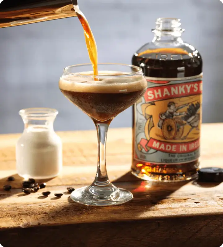 Pouring Shanky's Whip Black Irish Whiskey into a cocktail glass, showcasing rich coffee and creamy texture.