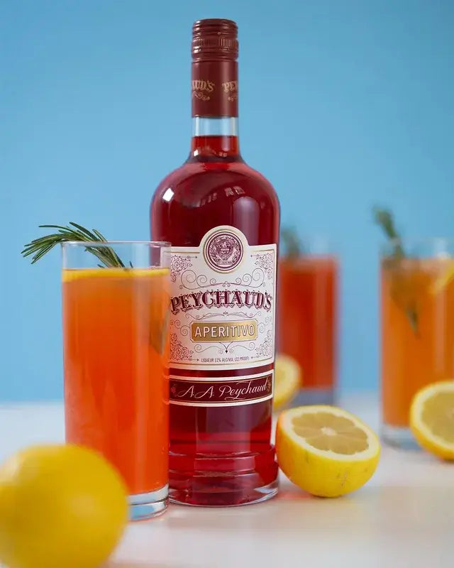 Peychaud's Aperitivo bottle with citrus cocktails and fresh lemons on a light background.