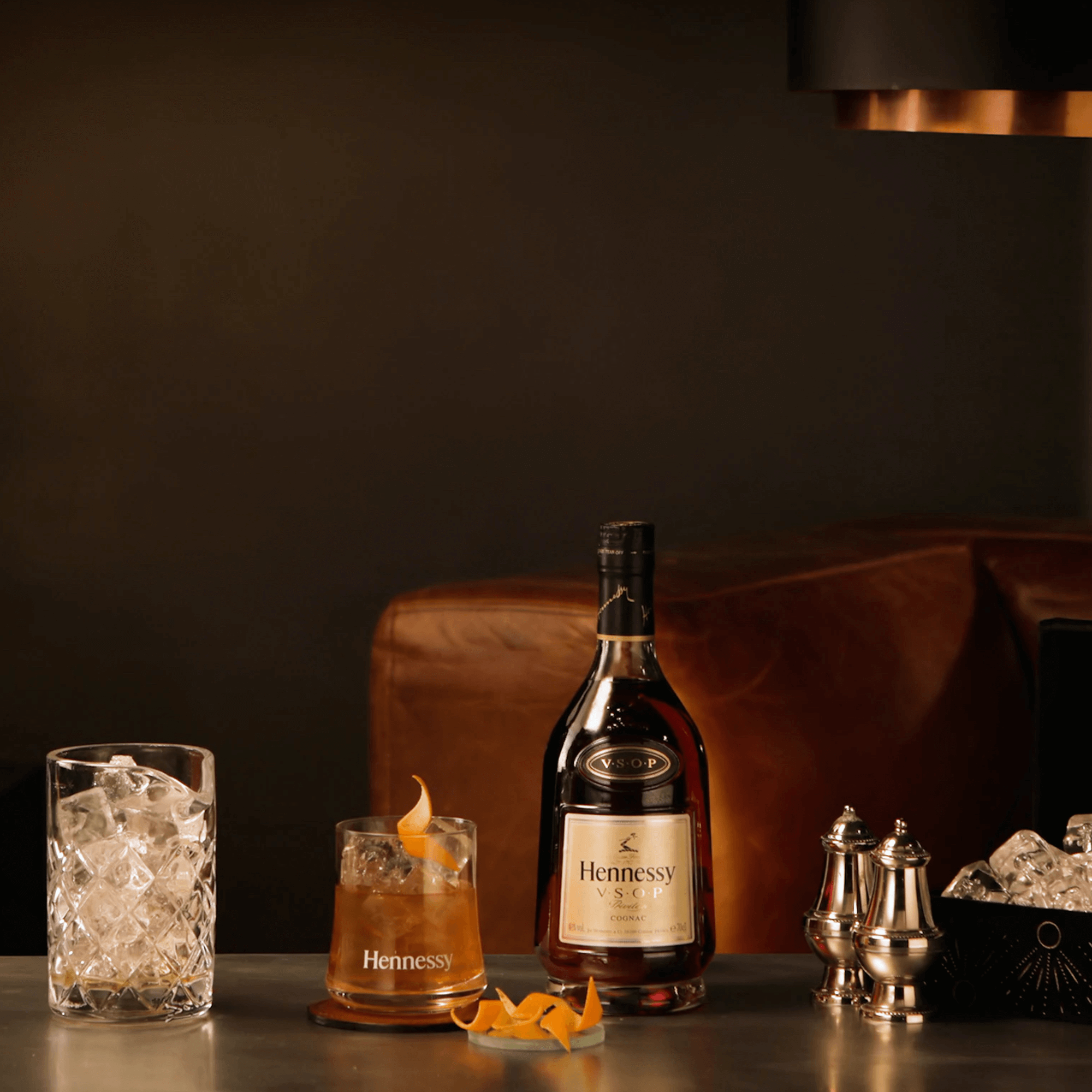 Hennessy VSOP Privilège 1.75L bottle with a glass of cognac and ice, elegant setting with a modern ambiance.