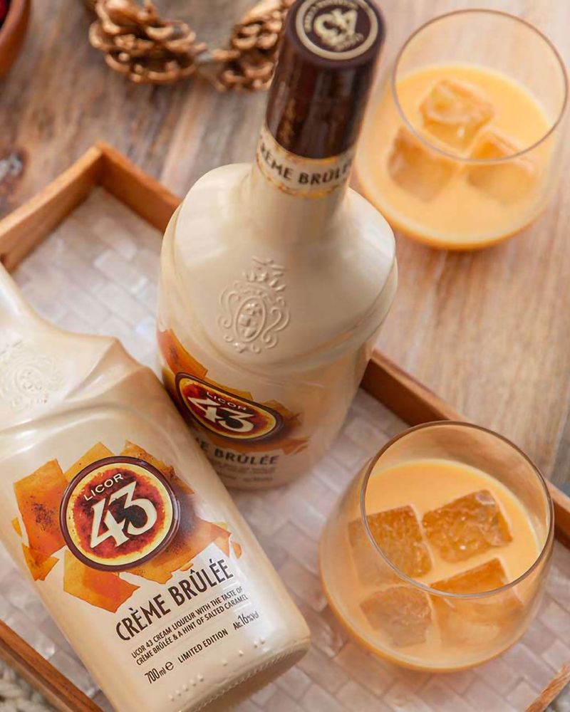 Bottle of Licor 43 Crème Brûlée liqueur with glasses of creamy drink and ice cubes.