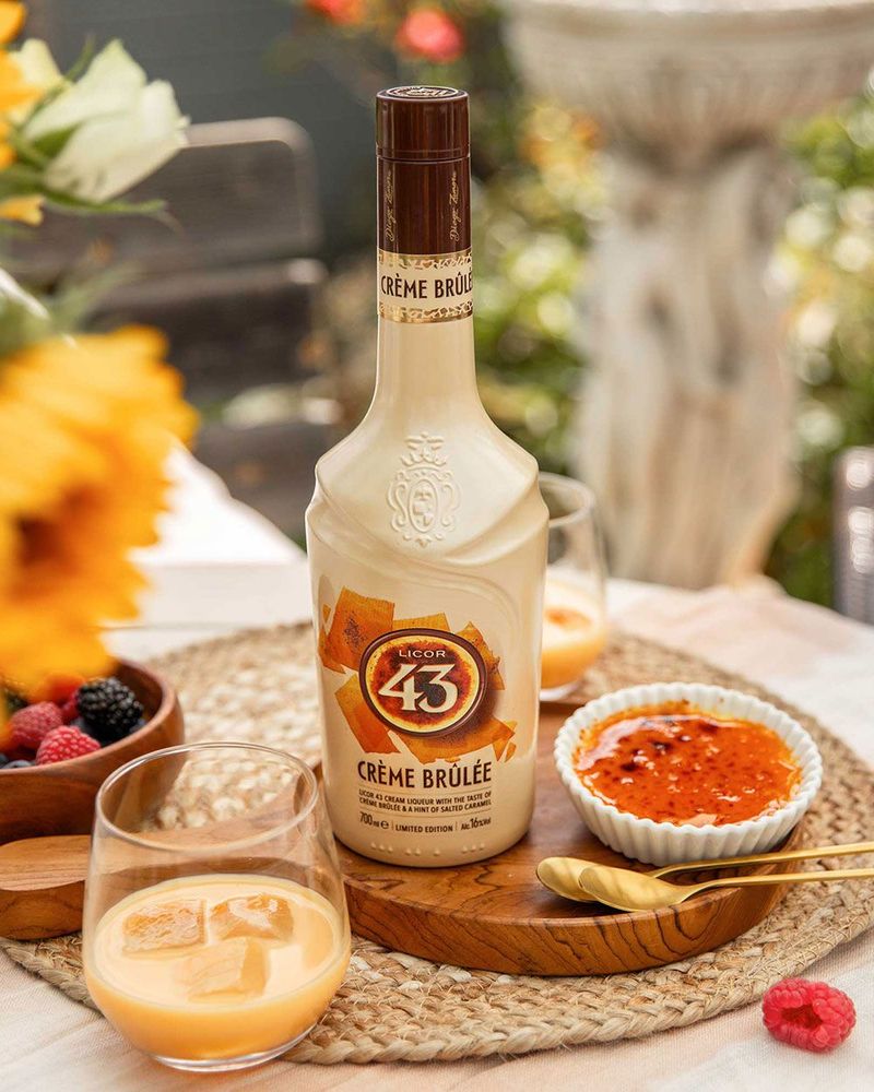 Licor 43 Crème Brûlée liqueur bottle surrounded by dessert and fruits, evoking a sweet, indulgent experience.