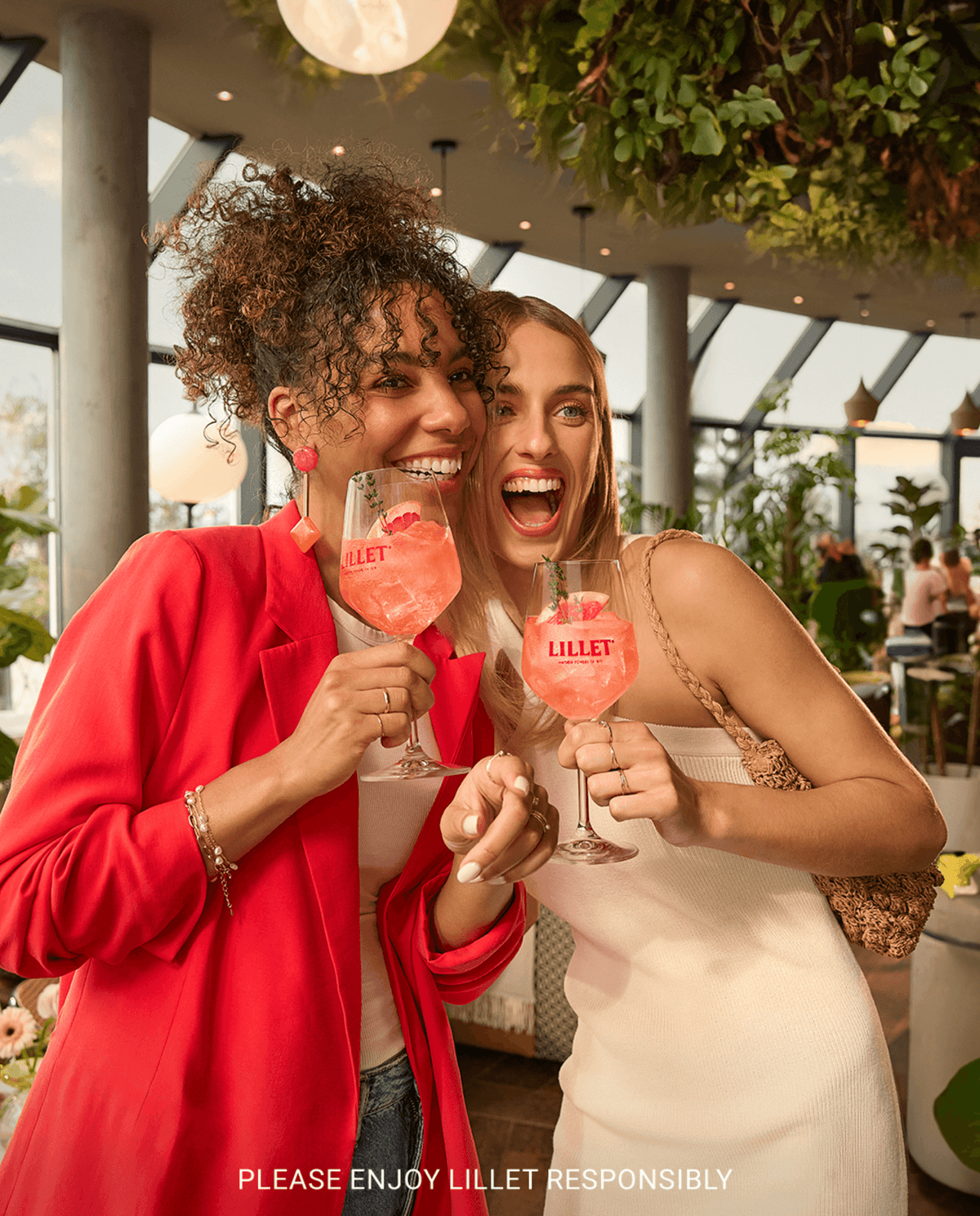 Two women joyfully toasting with Lillet Aperitif cocktails in a vibrant, stylish setting.