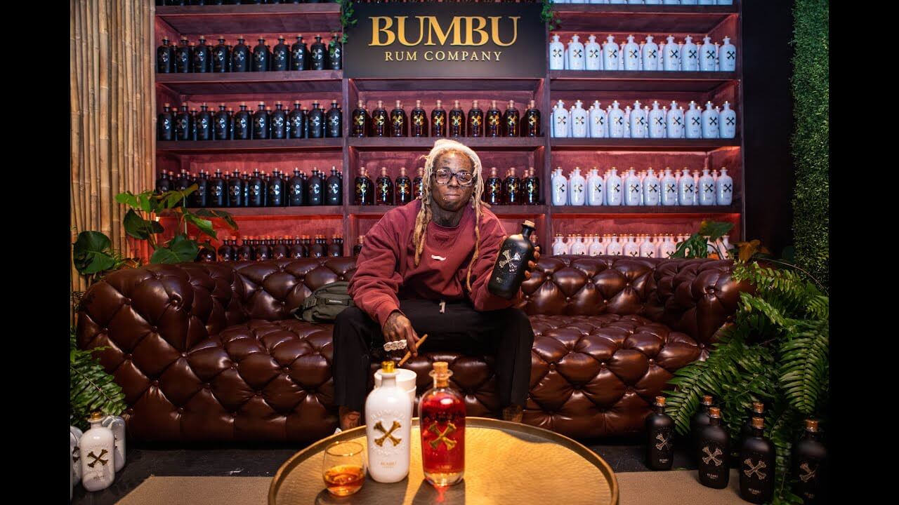 Lil Wayne showcases Bumbu XO Funeral Rum in a stylish venue, celebrating his 13th album release with limited edition spirits.