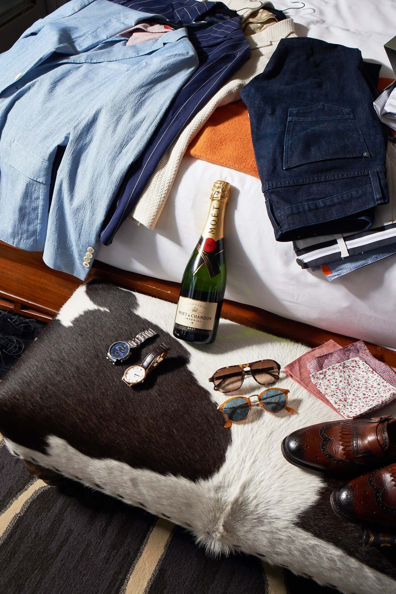 Stylish flat lay featuring Moët & Chandon Brut Impérial, elegant attire, sunglasses, and accessories on a decorative surface.