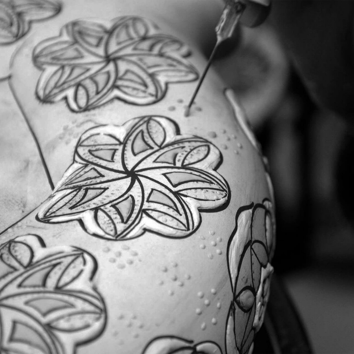 Artist detailing intricate floral patterns on a traditional Dia De Los Muertos sculpture.