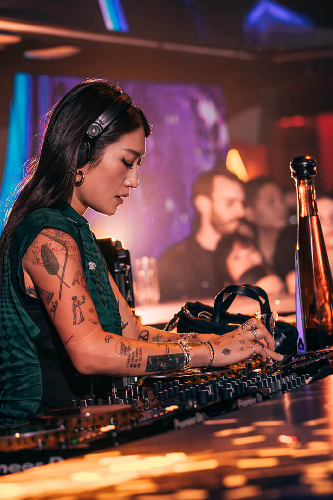 DJ Peggy Gou performing live with vibrant lighting and a bottle of Don Julio 1942 in the foreground.