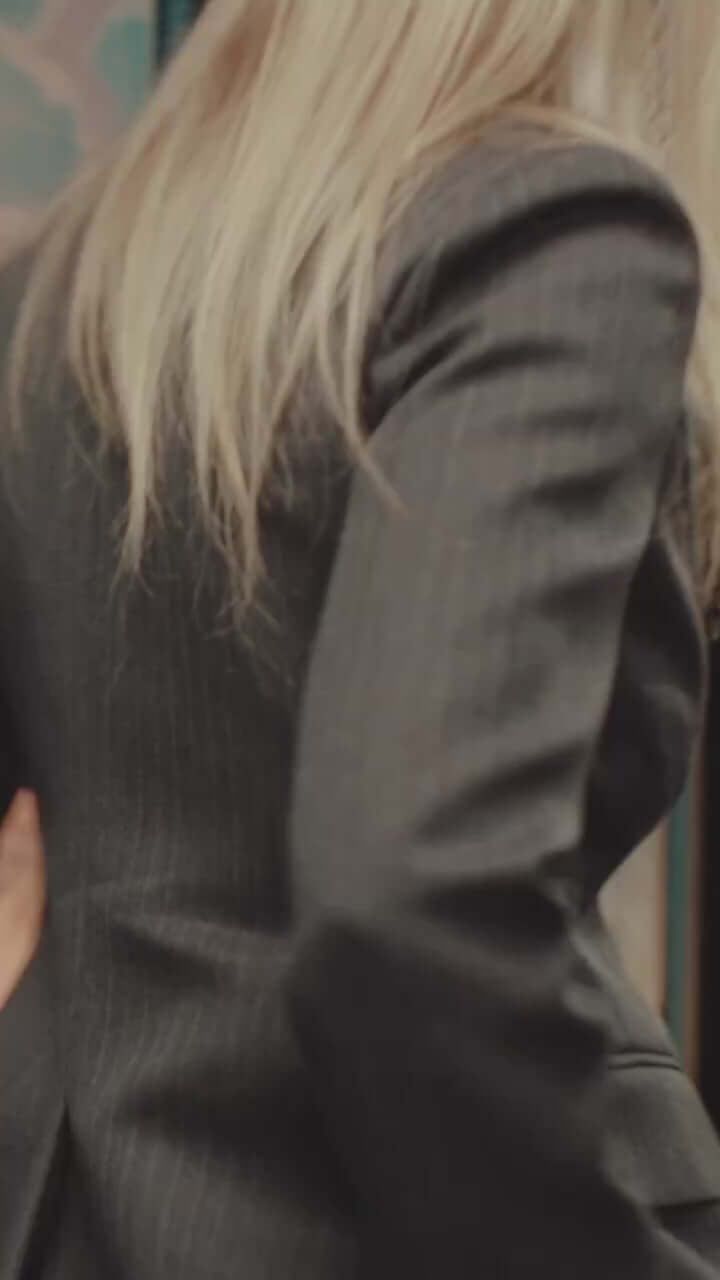 Woman in a stylish gray pinstripe blazer, showcasing modern fashion and elegance from a rear angle.