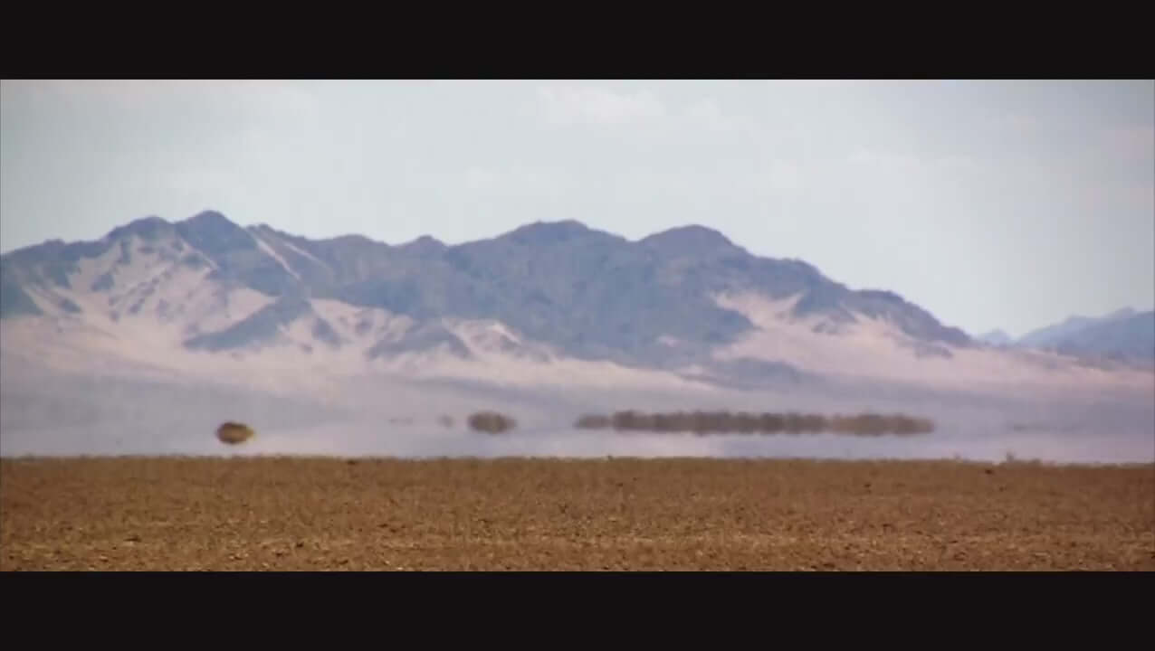 Expansive desert landscape with distant mountains and clear blue sky.