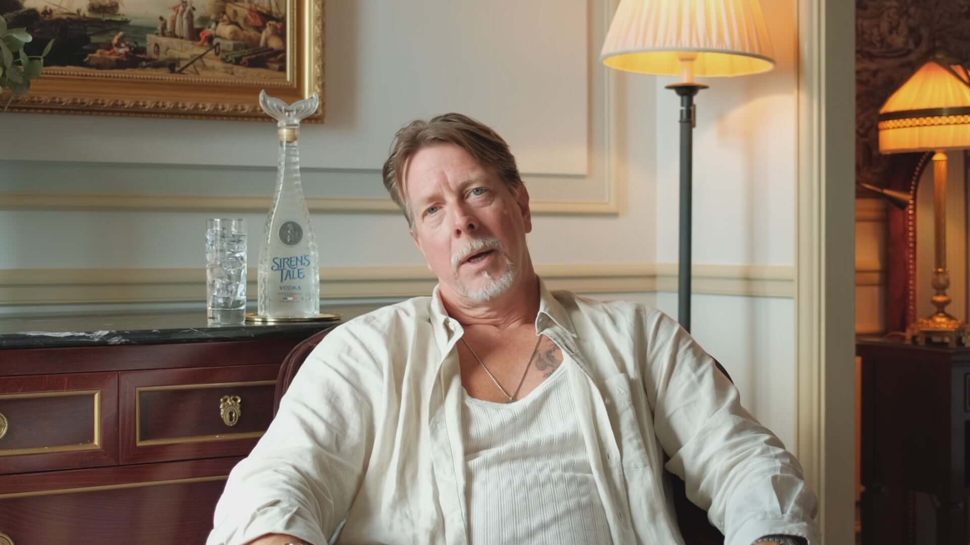 Man sitting in a stylish room with Siren's Tale Vodka bottle and glasses on display.
