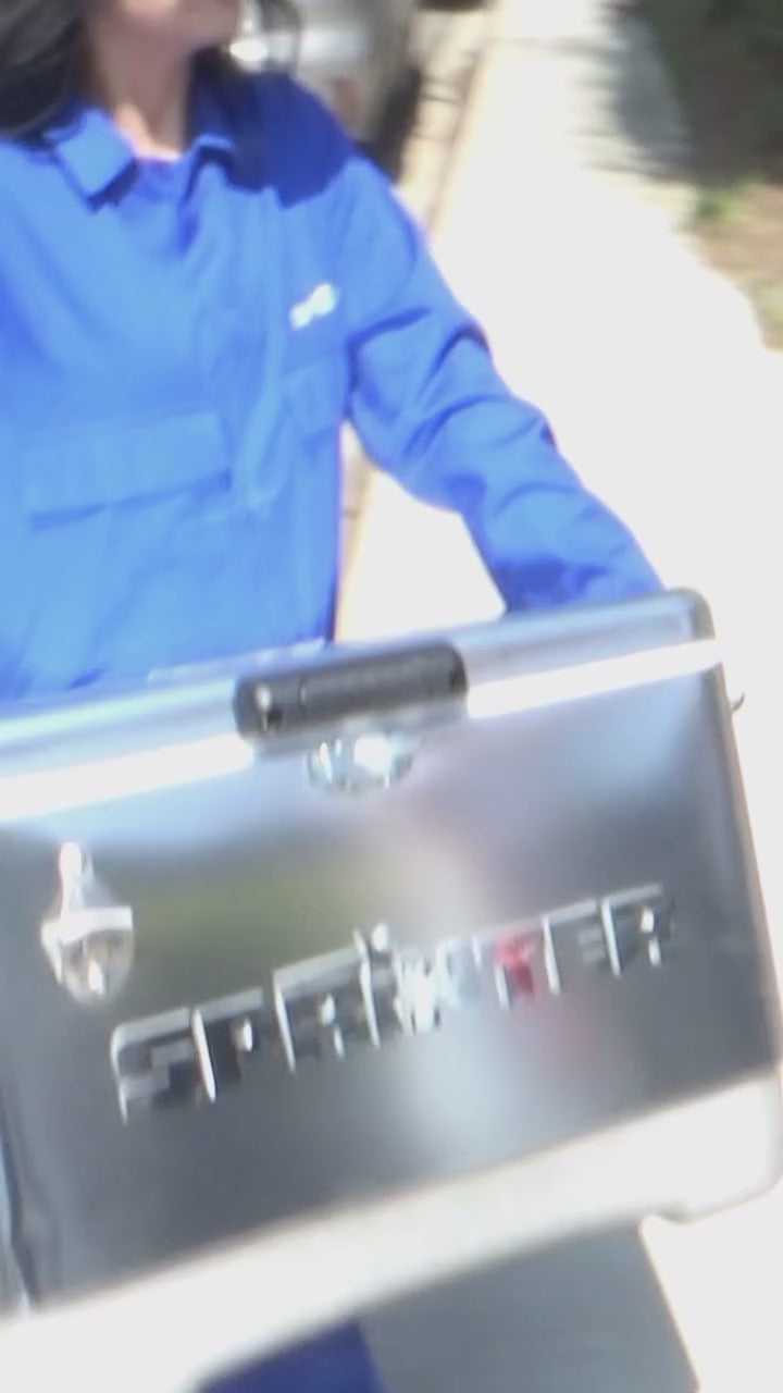 Person in blue outfit carrying a silver Sprinter cooler, ready for fun with vodka soda variety pack.