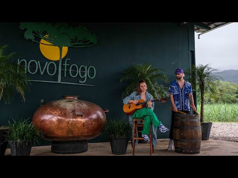 Two musicians performing near a copper still at Novo Fogo Cachaça distillery, showcasing its organic and traditional processes.
