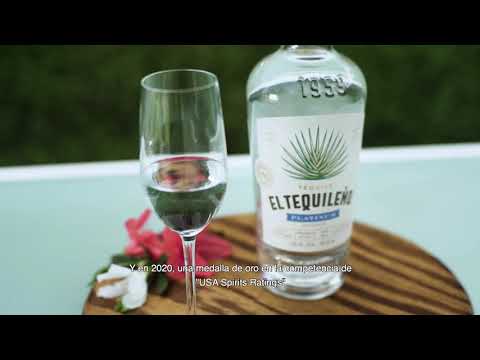 El Tequileño Platinum Blanco Tequila bottle beside a glass and garnishes on a wooden platter outdoors.