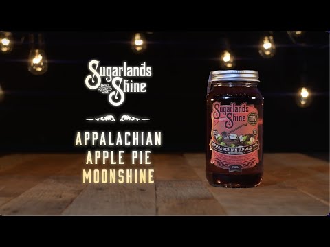 Sugarlands Shine Appalachian Apple Pie Moonshine in a jar against a rustic wooden background with lights.
