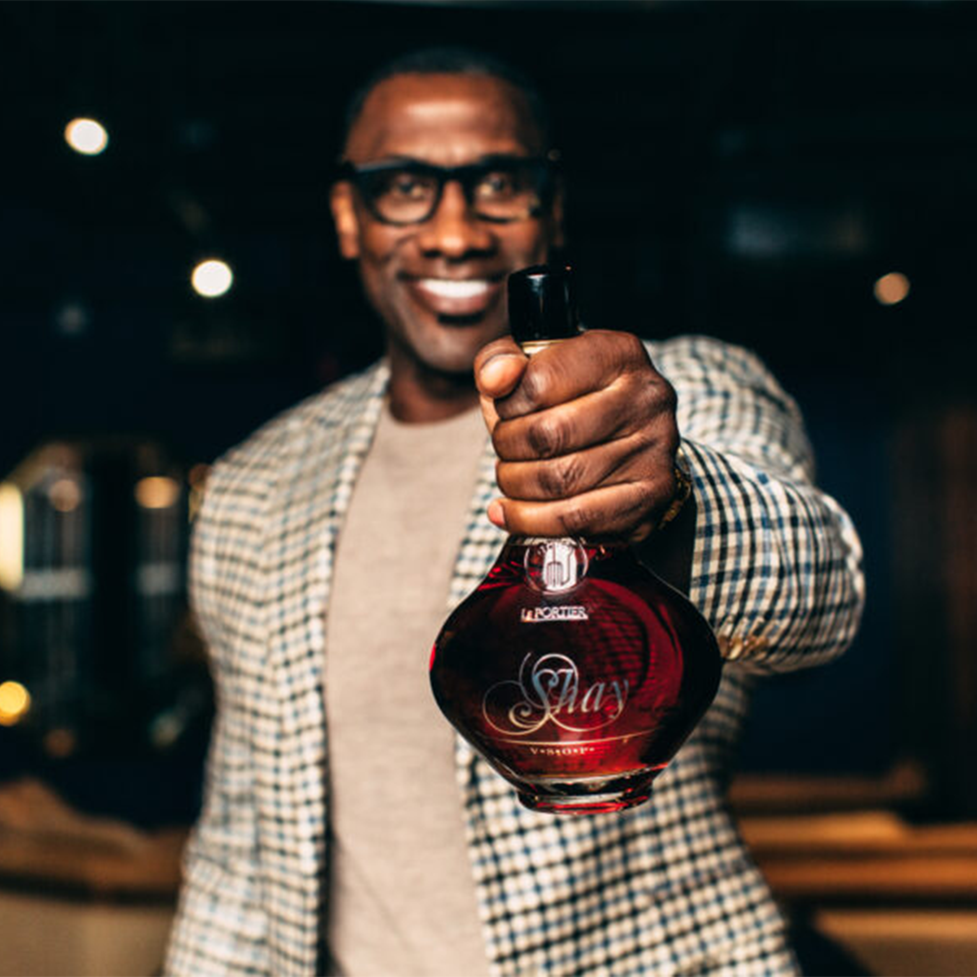 Man holding Le Portier Shay VSOP Cognac bottle, showcasing its elegant design in a stylish setting.