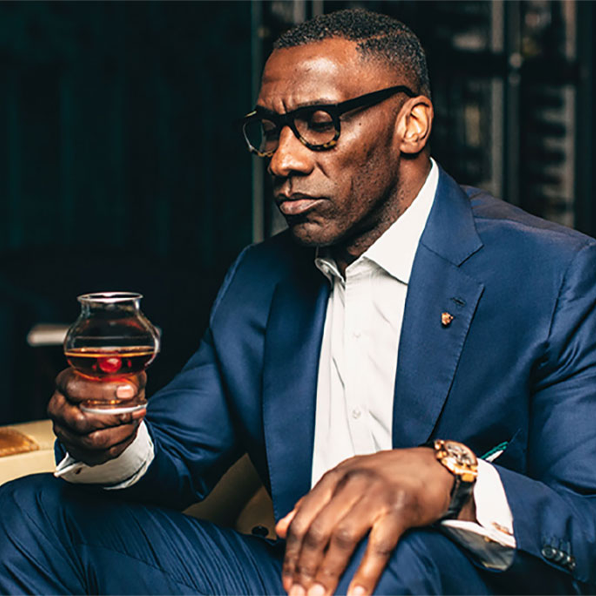 Man in a blue suit savoring Le Portier Shay VSOP Cognac from a glass, showcasing elegance and sophistication.