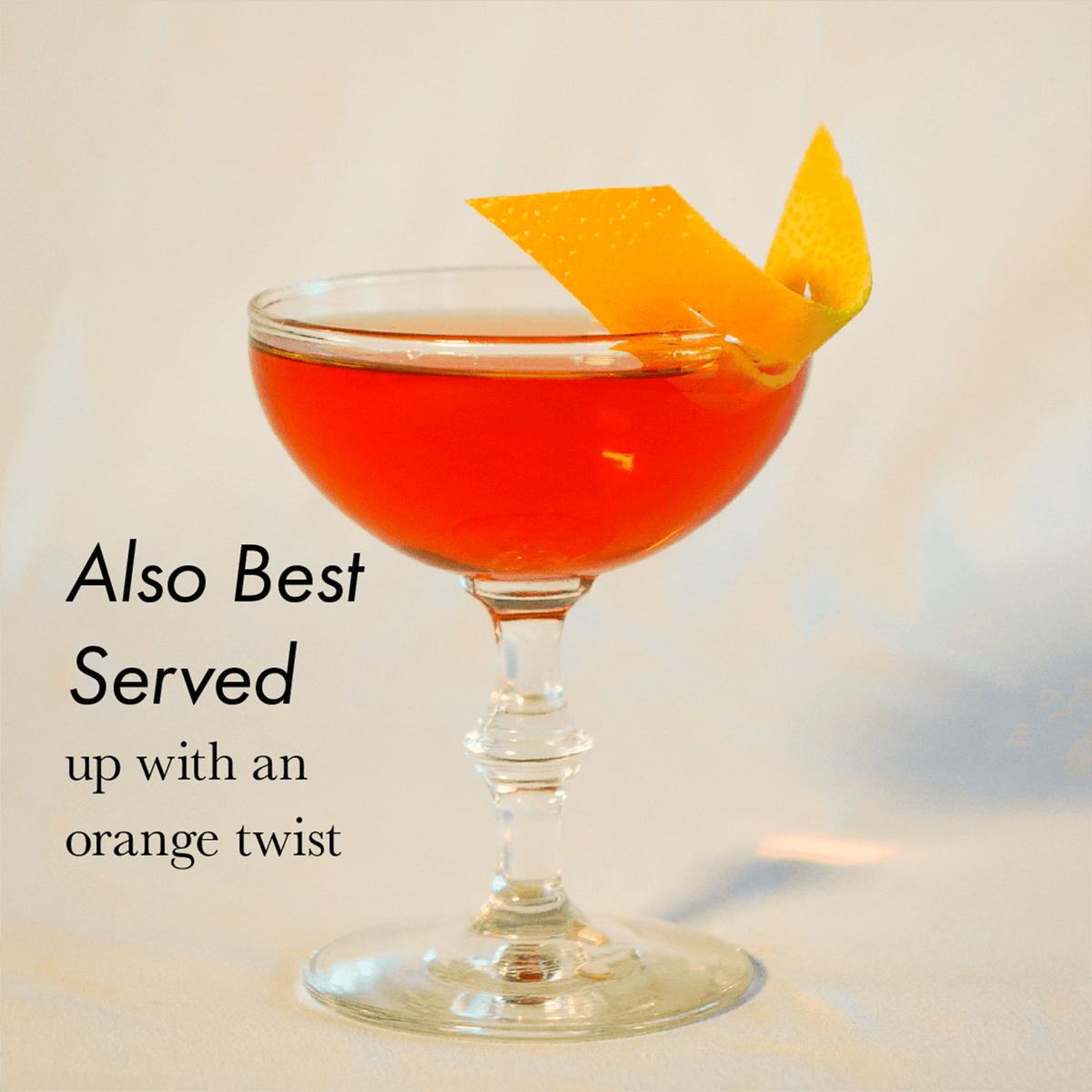 Freitag Negroni cocktail in a glass with an orange twist garnish on a white background.