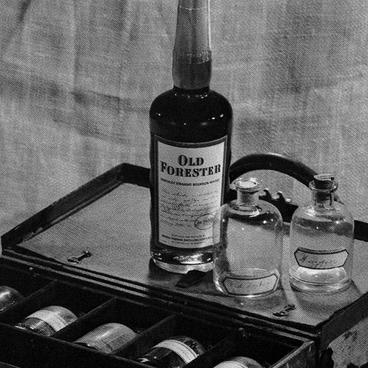 Old Forester Single Barrel Barrel Proof Bourbon alongside vintage glass bottles in a wooden box.