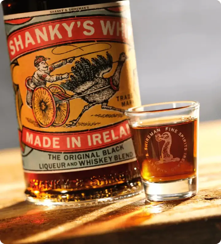 Shanky's Whip Black Irish Whiskey bottle with a shot glass, showcasing its rich vanilla and caramel flavors.