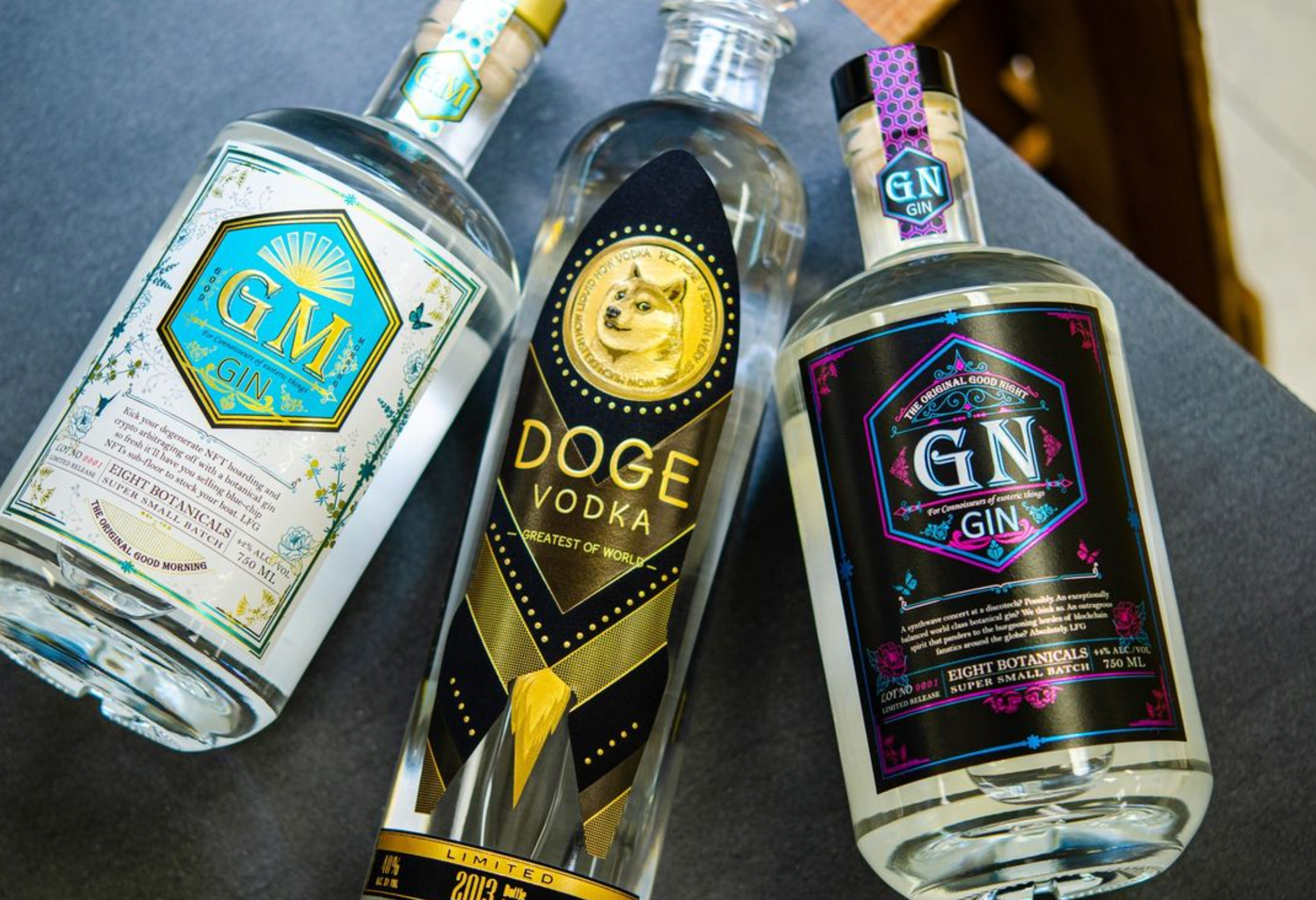 Three bottles of gin and vodka: Good Night Gin, DOGE Vodka, and GM Gin on a dark surface.