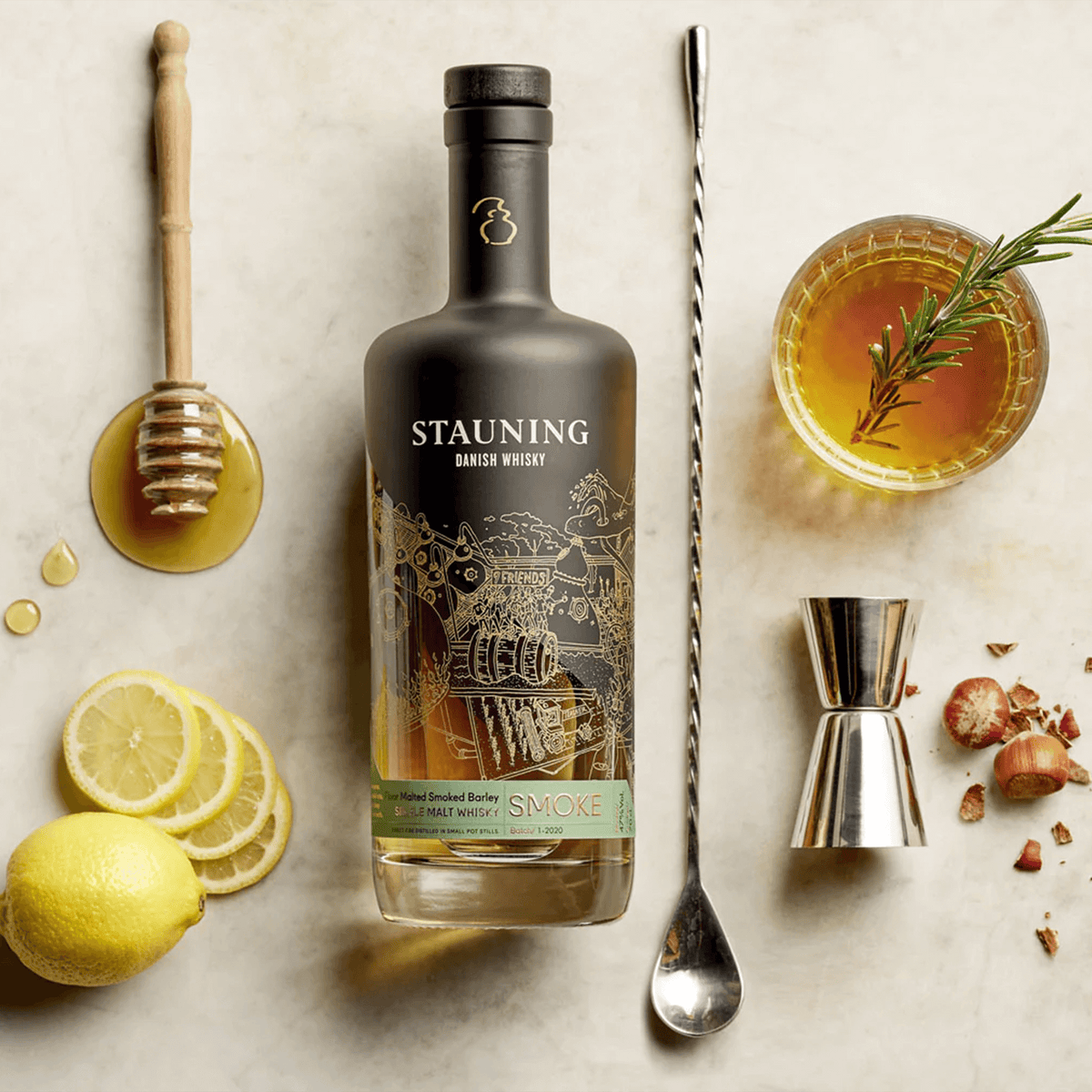 Bottle of Stauning Smoke Single Malt Whisky with cocktail ingredients, showcasing Danish craftsmanship.