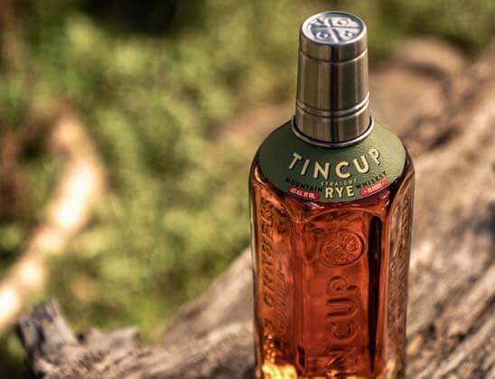 TINCUP Straight Rye Whiskey bottle on rustic wood background, celebrating Colorado mining heritage.