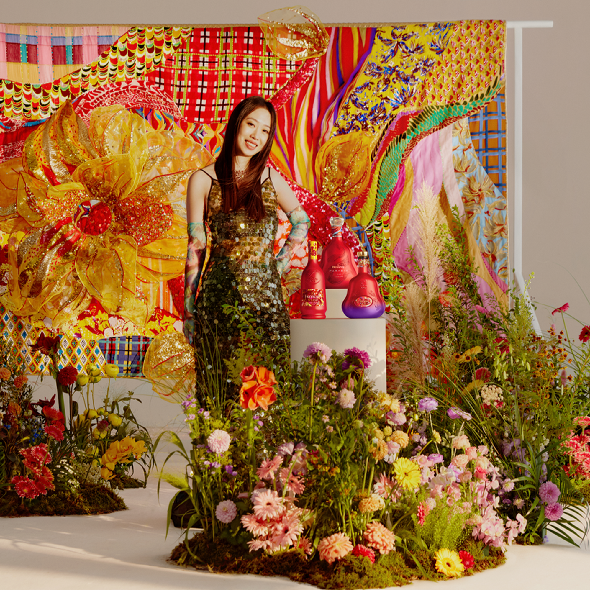 Artist Shuting Qiu poses with floral display and vibrant backdrop for Hennessy X.O. Lunar New Year 2025.
