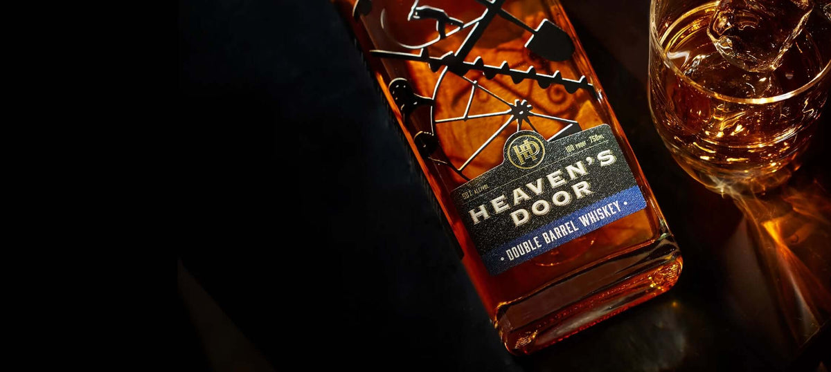 Heaven's Door Double Barrel American Whiskey bottle with glass on a dark surface, showcasing its rich amber color.