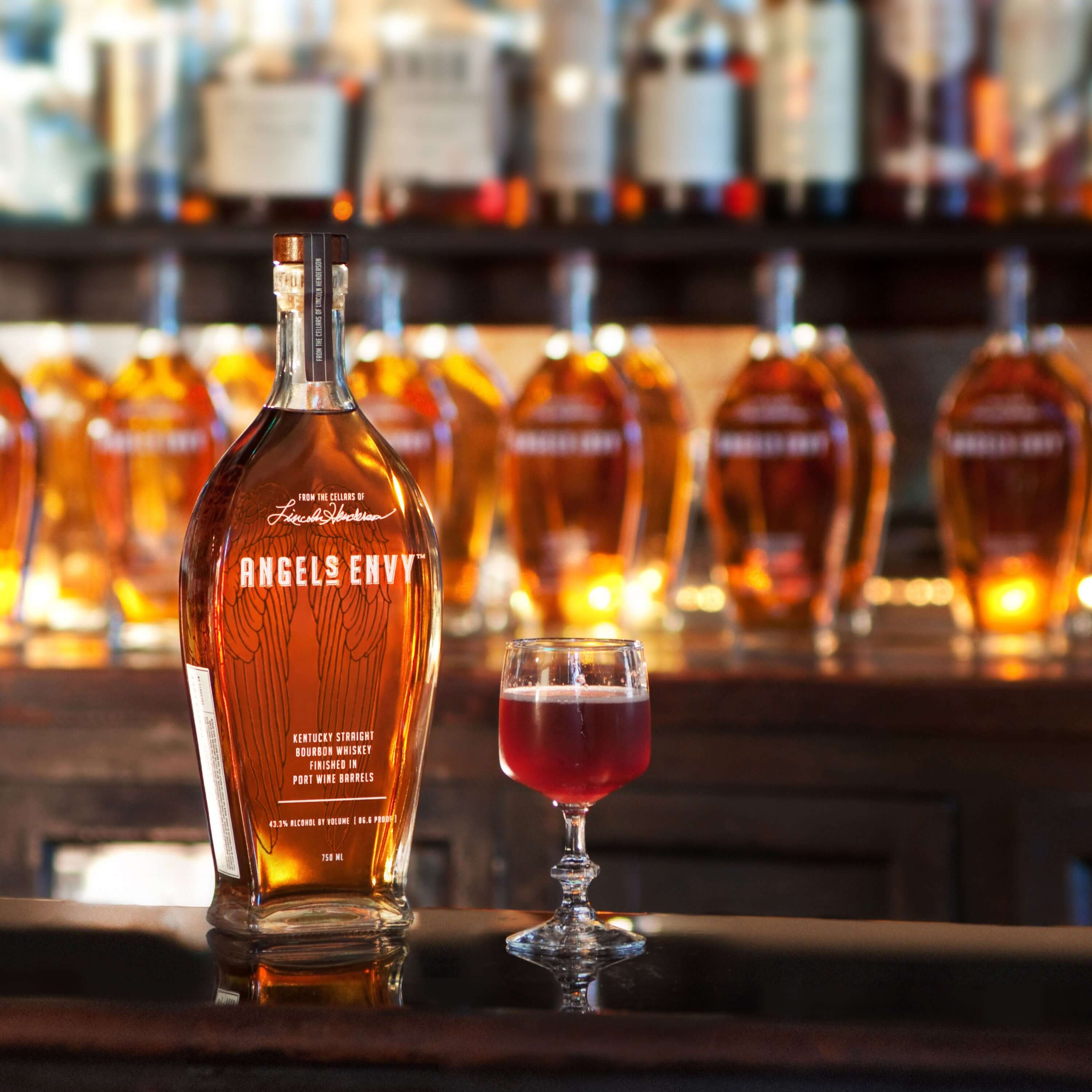 Angel's Envy Kentucky Straight Bourbon bottle with a glass of bourbon cocktail on a bar counter.