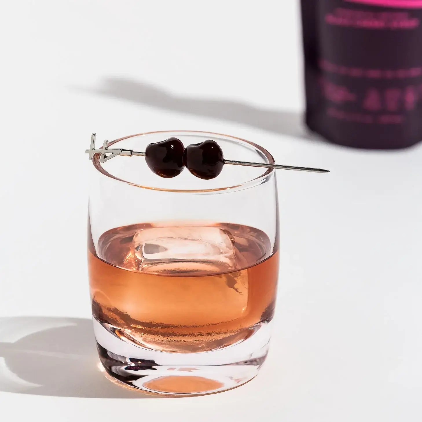 Cocktail glass with Filthy Foods Black Cherry Syrup and Amarena cherries on a skewer, perfect for cocktails.