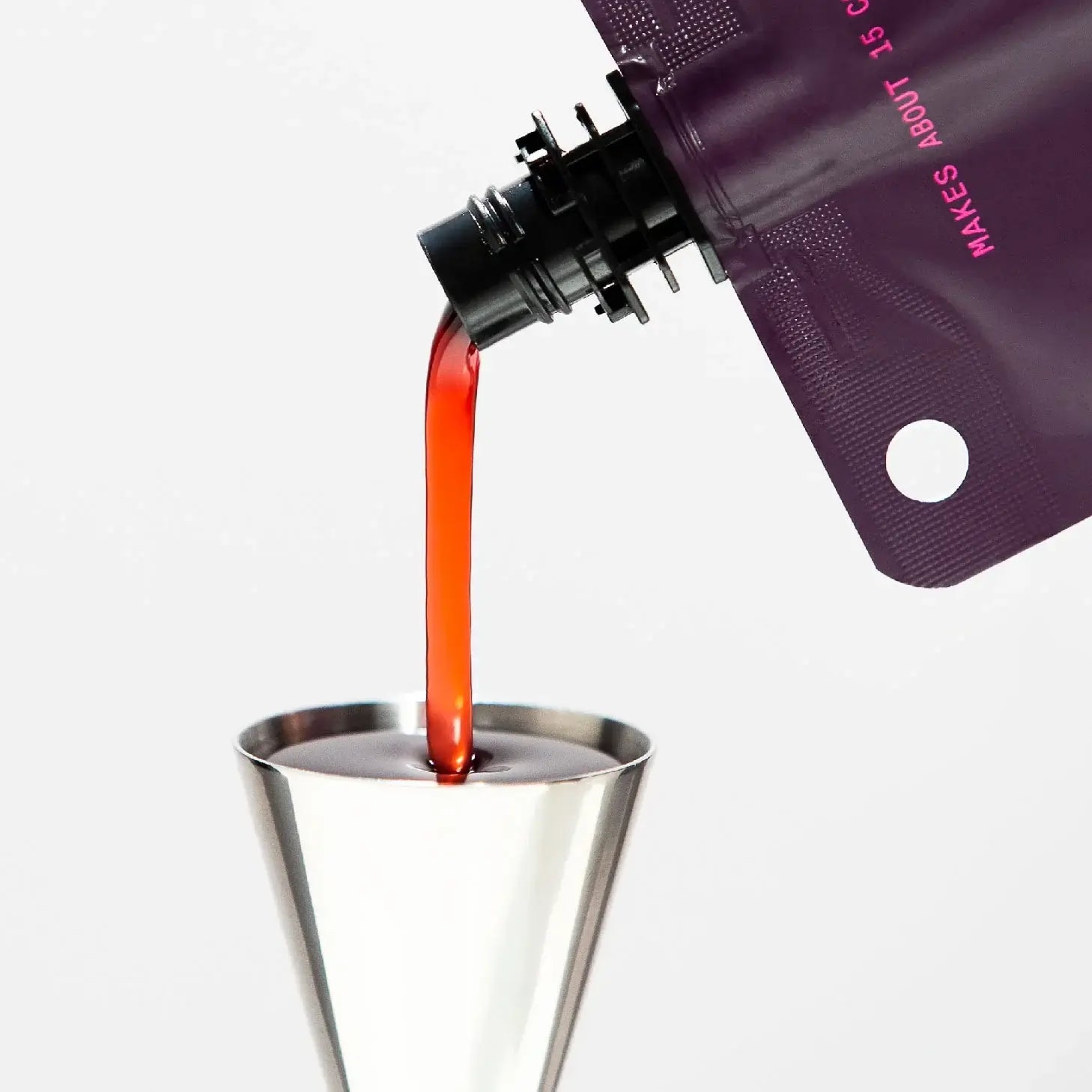 Pouring Filthy Foods Black Cherry Syrup from a pouch into a jigger for cocktail preparation.