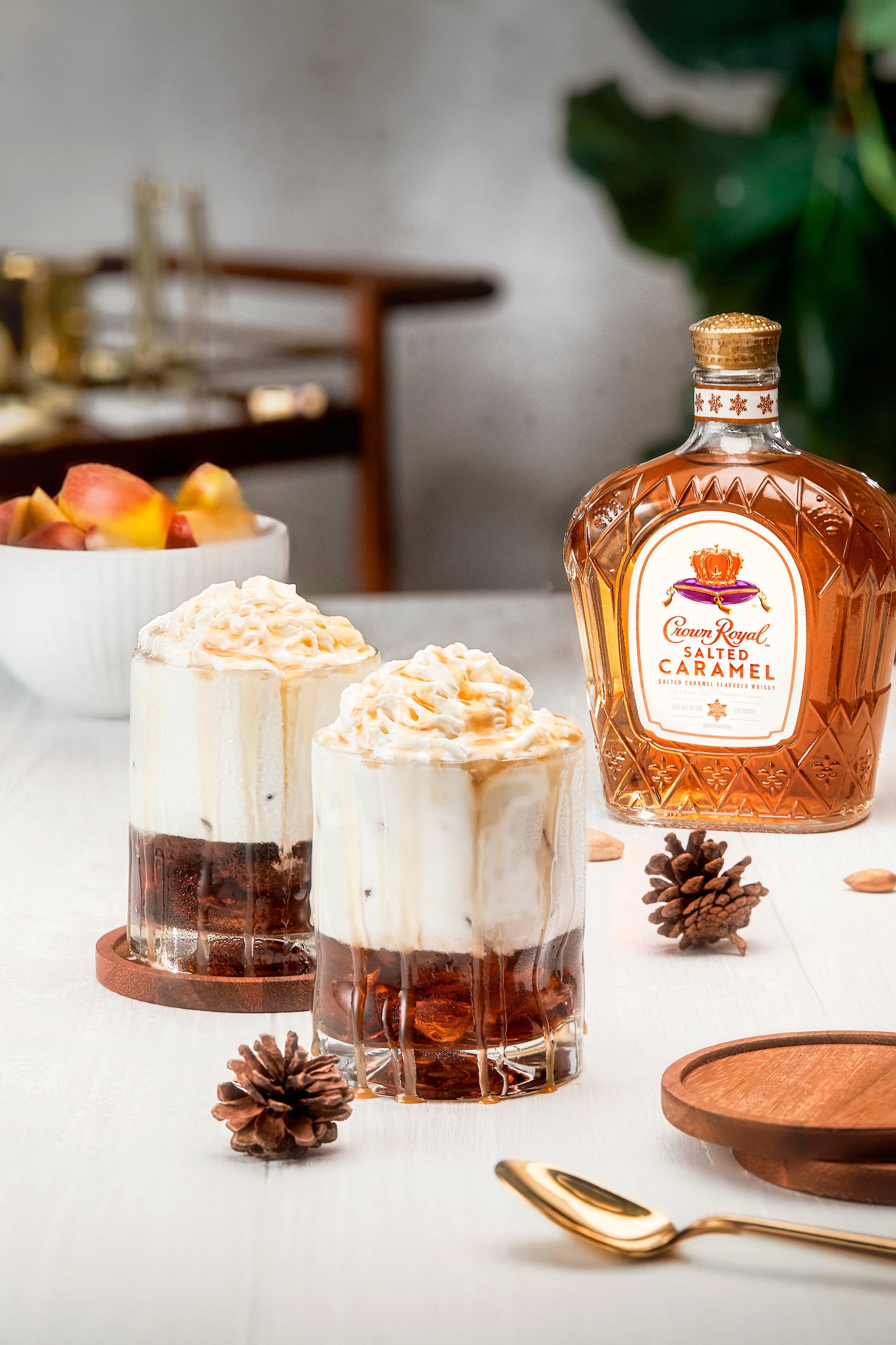 Crown Royal Salted Caramel whisky served in glasses with whipped cream and garnished, surrounded by pinecones.