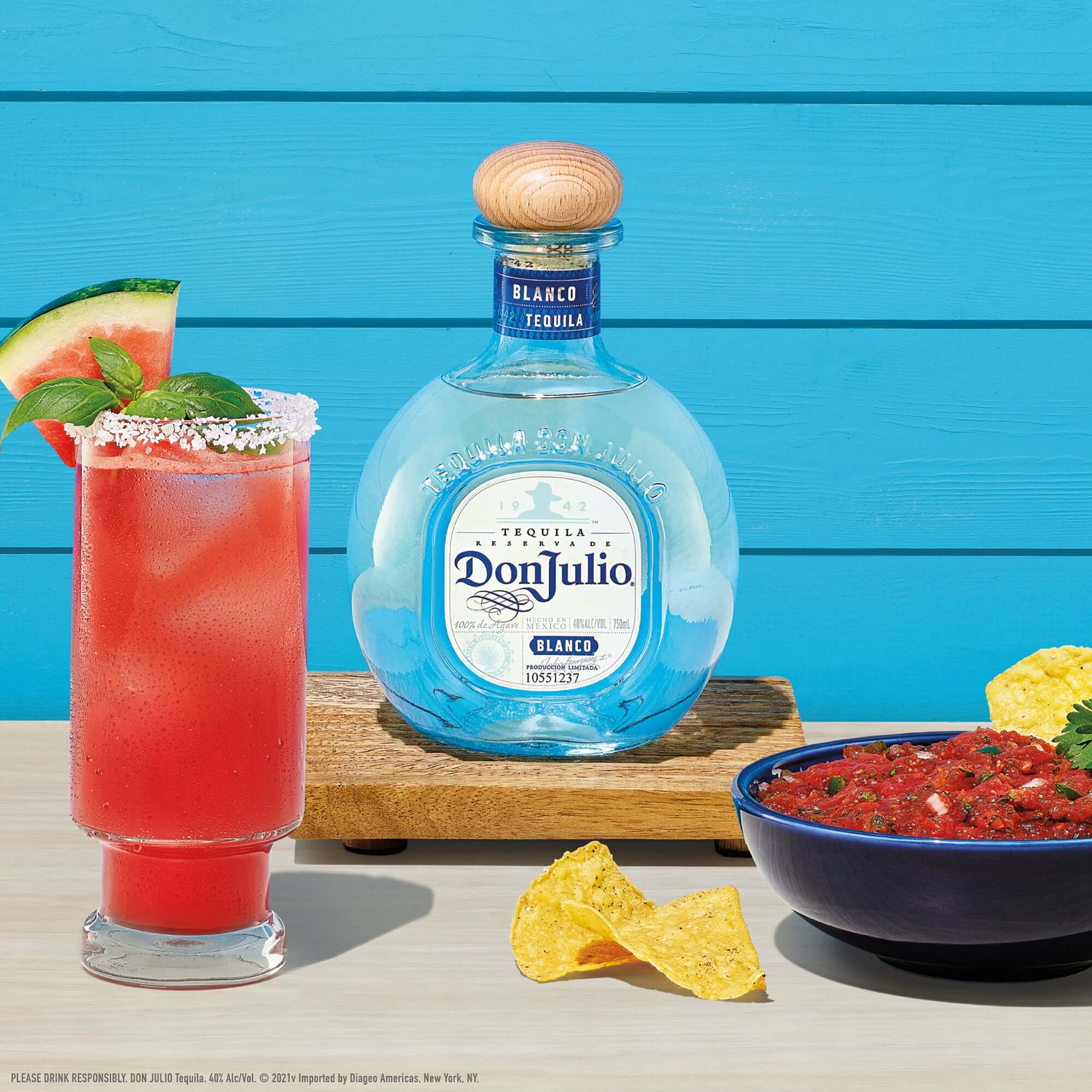 Don Julio Blanco Tequila bottle with a refreshing cocktail, chips, and salsa on a colorful background.