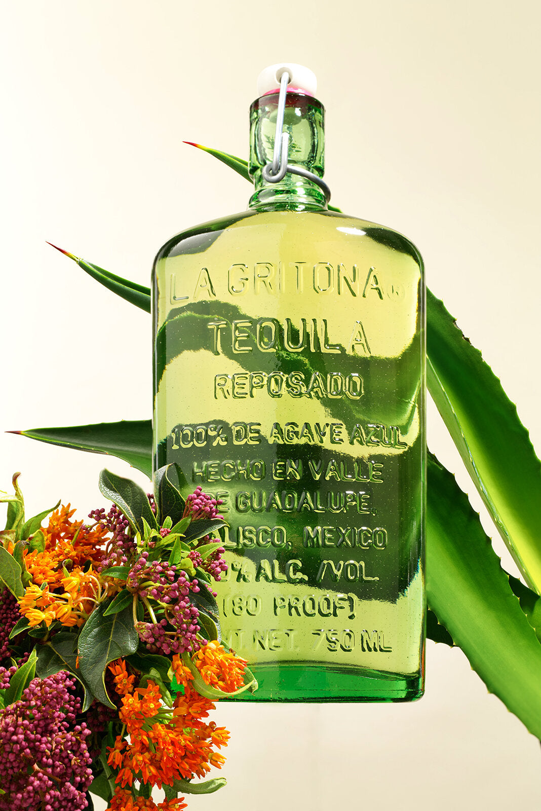 La Gritona Reposado Tequila bottle with agave leaves and colorful flowers, highlighting premium quality and craftsmanship.