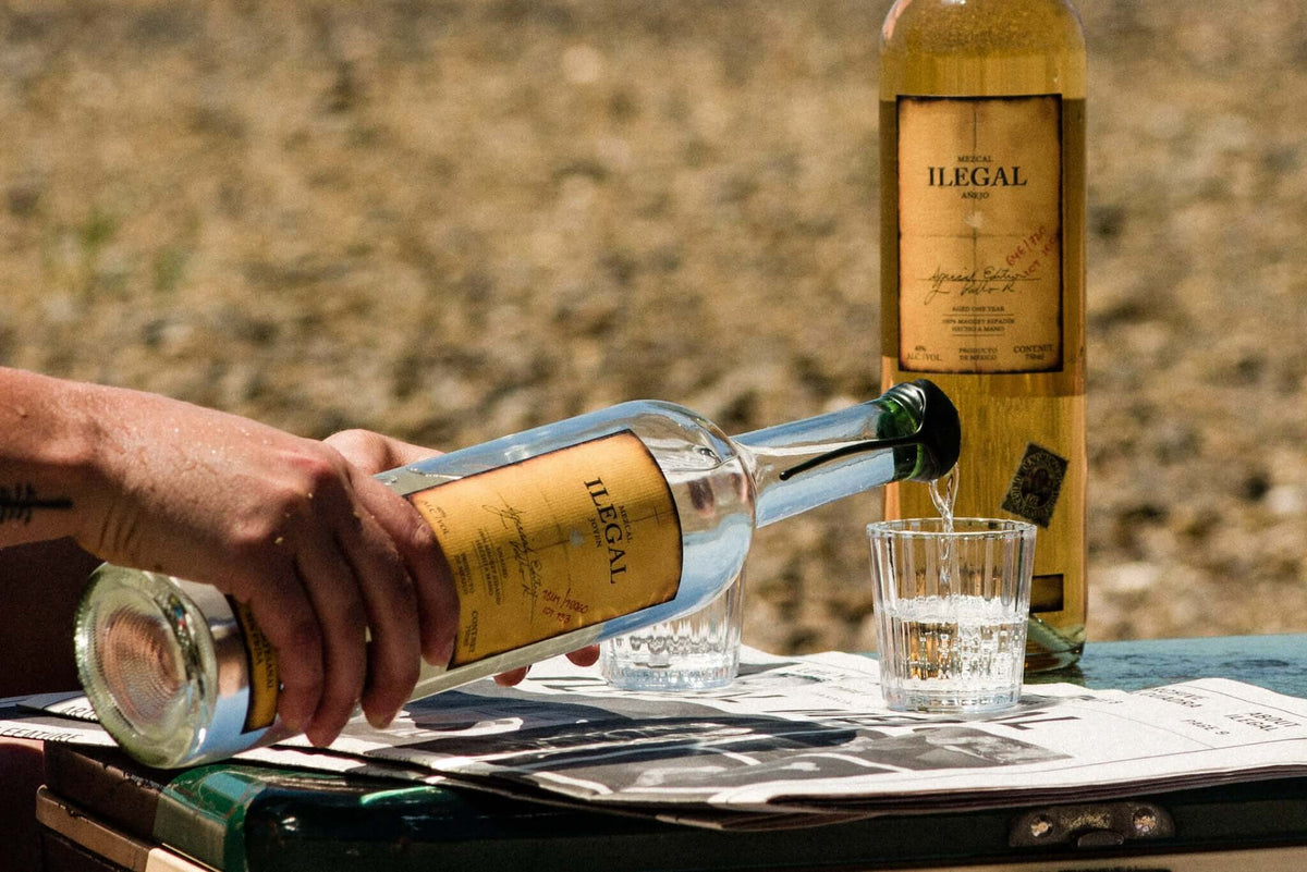 Pouring Ilegal Mezcal Añejo into a glass, showcasing its rich flavor and premium quality.