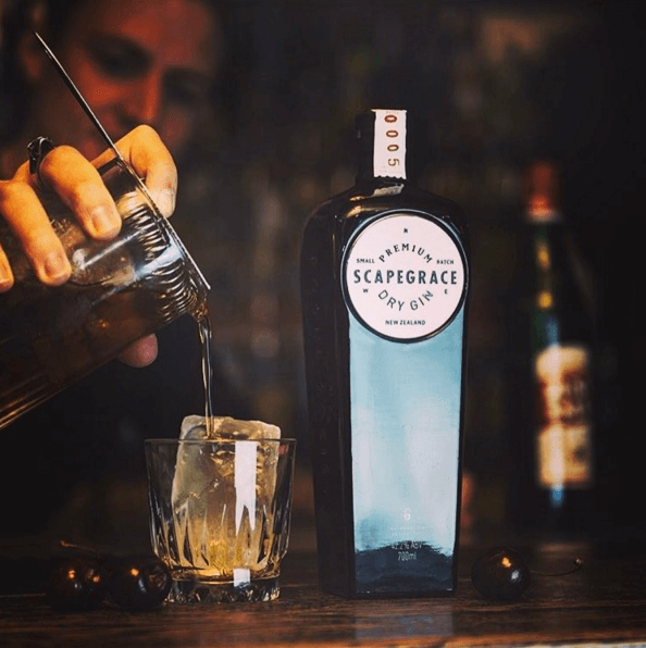 Pouring Scapegrace Dry Gin from New Zealand into a glass with ice, showcasing its premium quality.