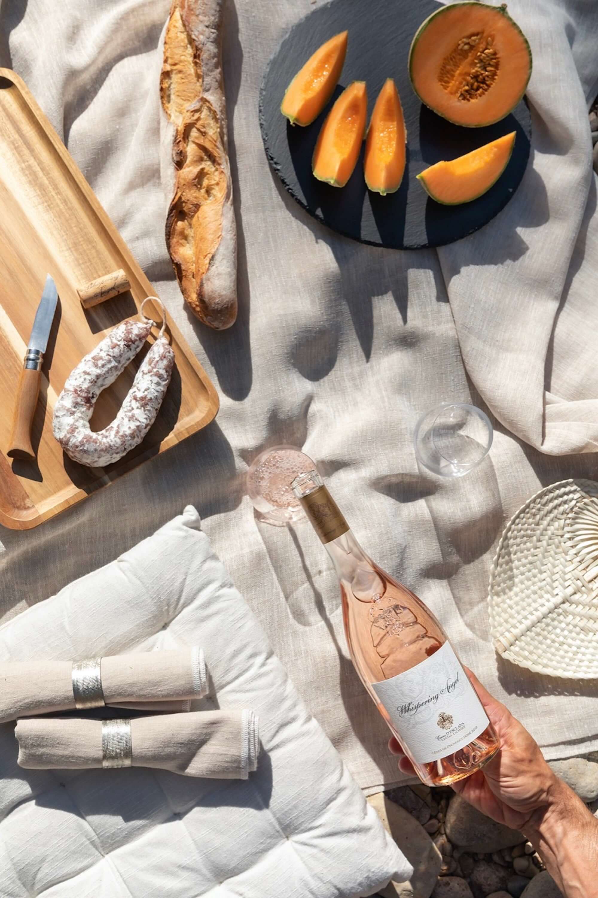 Château D'esclans Whispering Angel Rosé 750ml served with fresh bread, melon, and a cozy picnic setup.