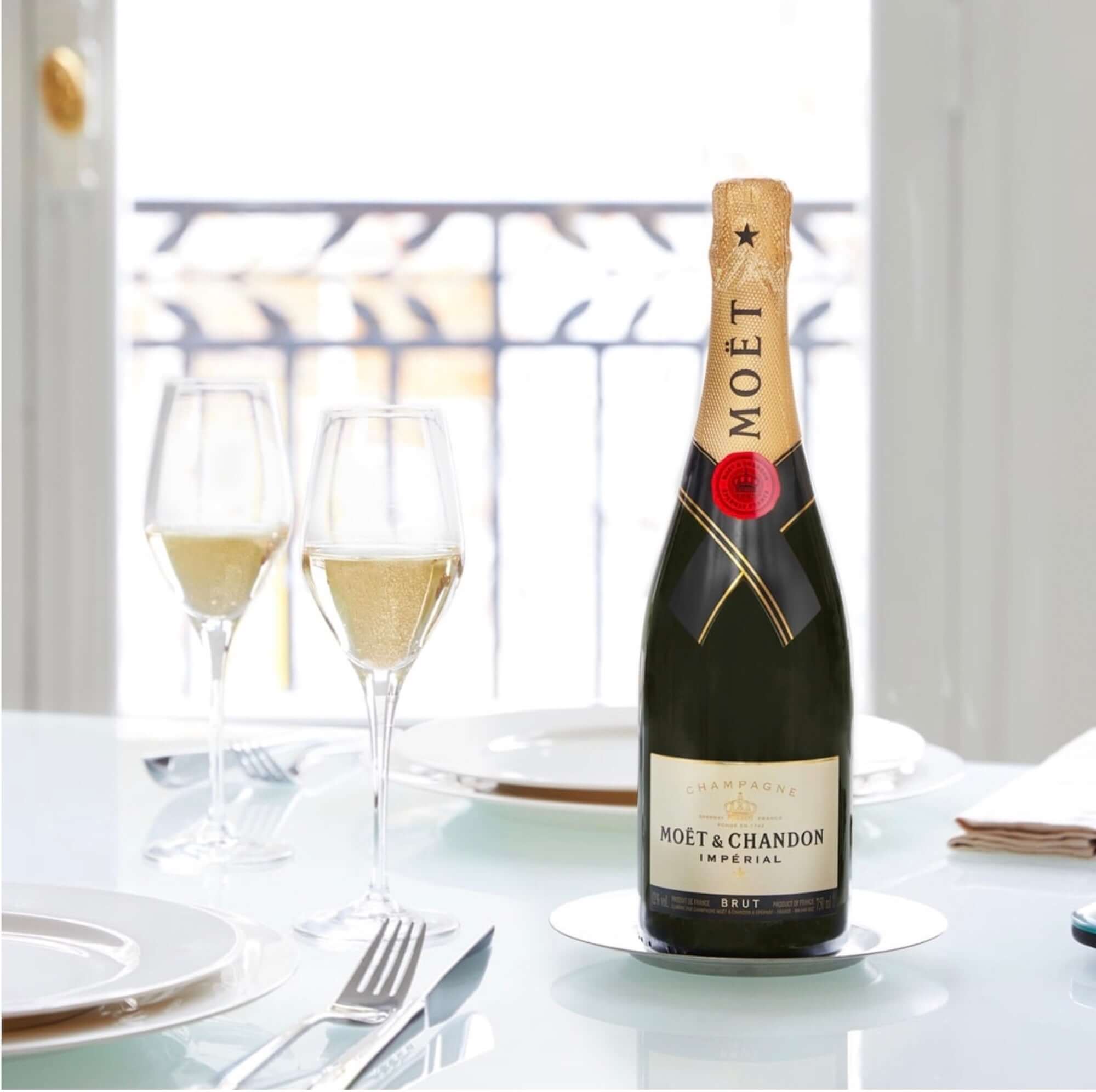 Bottle of Moët & Chandon Brut Impérial champagne on a table with flutes, symbolizing celebration and elegance.